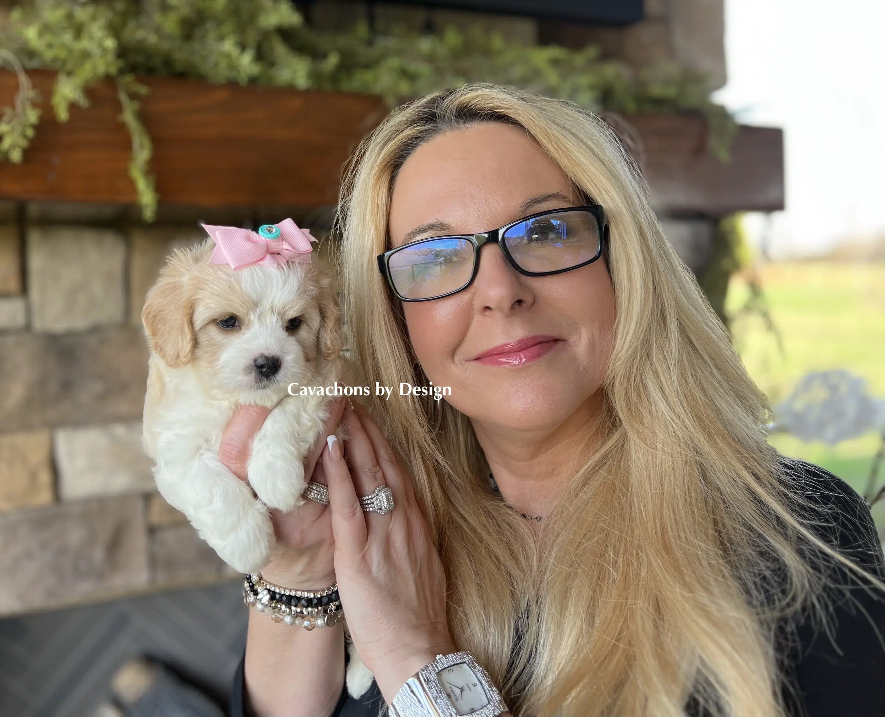 Smiling woman holding an adorable Cavachon puppy with a soft, hypoallergenic coat.